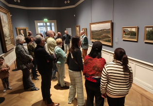 Een groep bezoekers bekijkt schilderijen in een museum.
