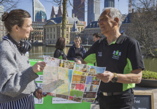 A woman and a man are looking at a map by the Hofvijver.