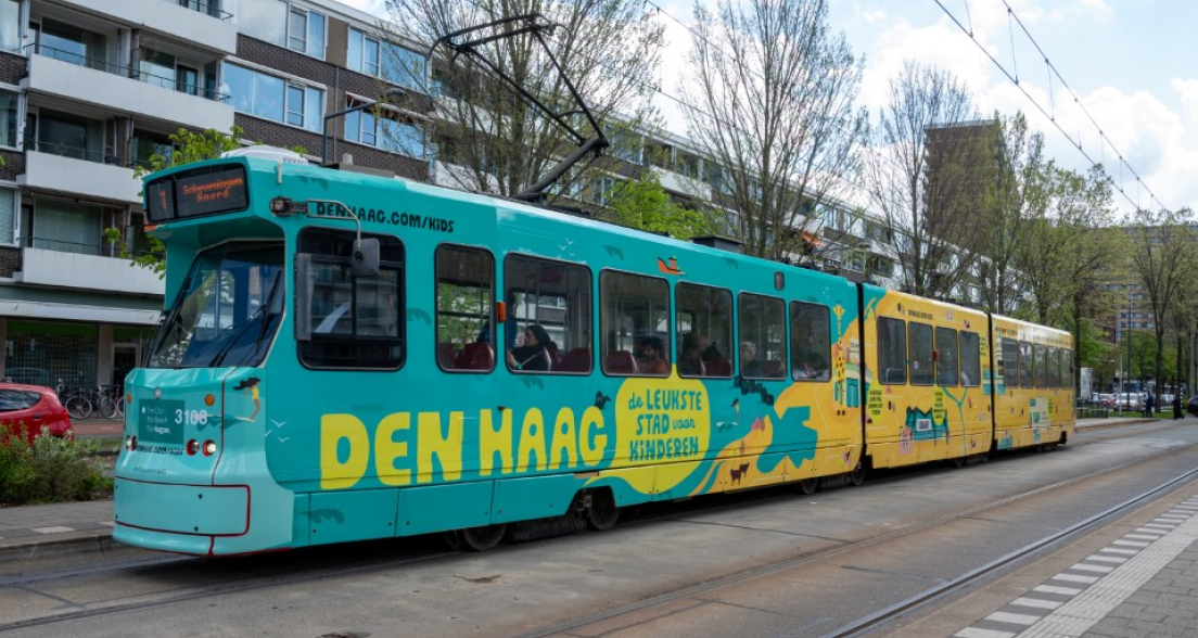 Kleurige tram met 'Den Haag, de leukste stad voor kinderen' in de stad.