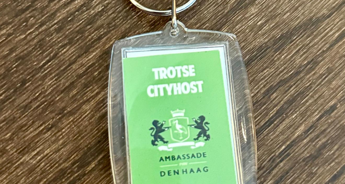 Groene sleutelhanger met de tekst 'Trotse Cityhost' en het wapen van Den Haag.
