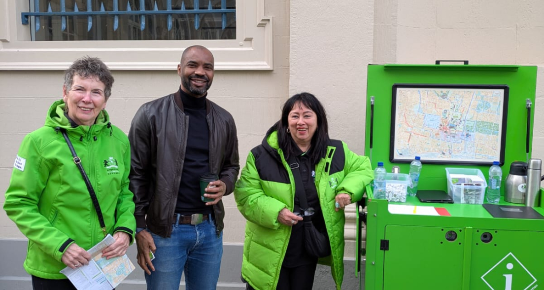 Drie mensen staan bij een groen informatiepunt met een kaart.