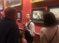 Een gids legt iets uit aan bezoekers in een museum.