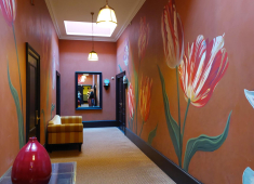 Een gang met geschilderde tulpen op de muren en een spiegel.