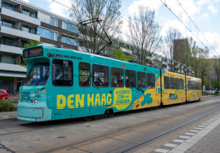 Kleurige tram met 'Den Haag, de leukste stad voor kinderen' in de stad.