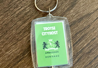 Groene sleutelhanger met de tekst 'Trotse Cityhost' en het wapen van Den Haag.