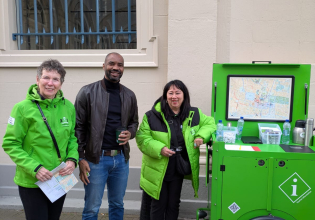 Drie mensen staan bij een groen informatiepunt met een kaart.