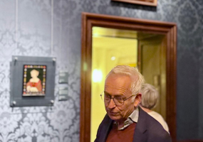 Een man in een museum met schilderijen op de muur.