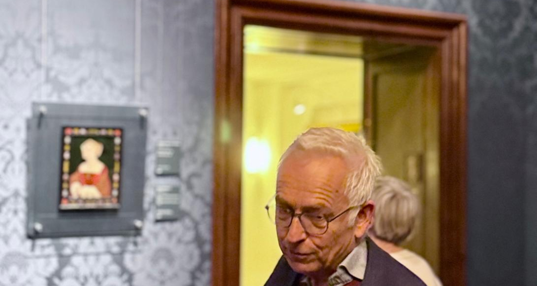 Een man in een museum met schilderijen op de muur.
