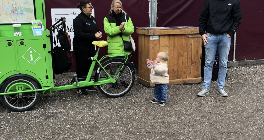 Een kind staat voor een groene fiets met volwassenen in Den Haag.