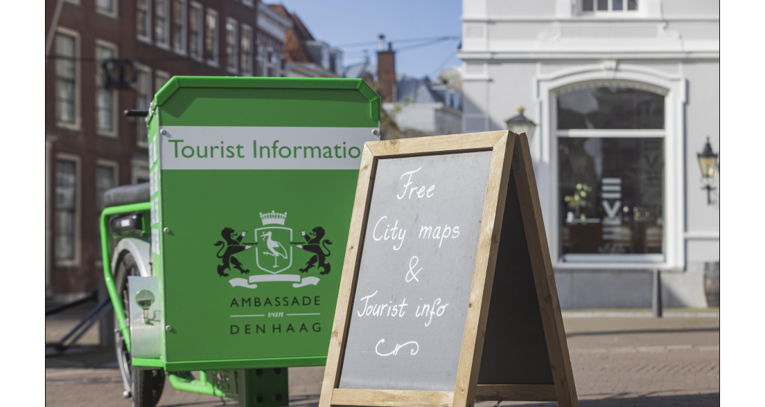 Groene fiets met toeristeninformatie en een bord met gratis stadskaarten
